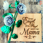 rechteckiges Holzbrett mit Gravur "einen Engel ohne Flügel nennt man Mama", links auf dem Holzbrett ist ein Strauß aus drei weißen Edelstahlrosen angebracht, weiße Rosenblütenblätter, grüner Rosenstiel und grüne Rosenblätter, in Handarbeit gefertigt